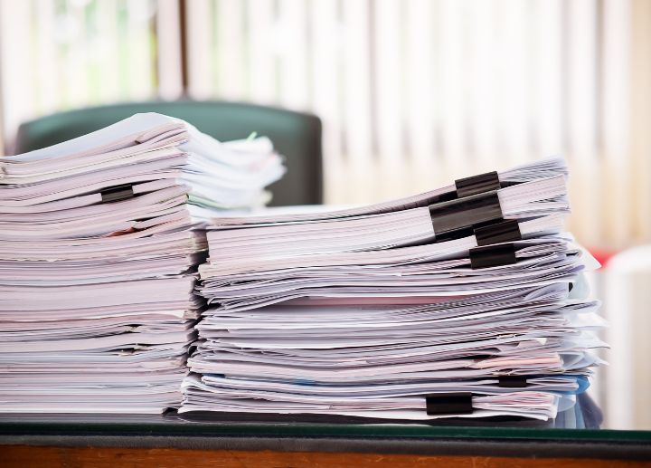 Stacked piles of paper documents clipped together on a desk